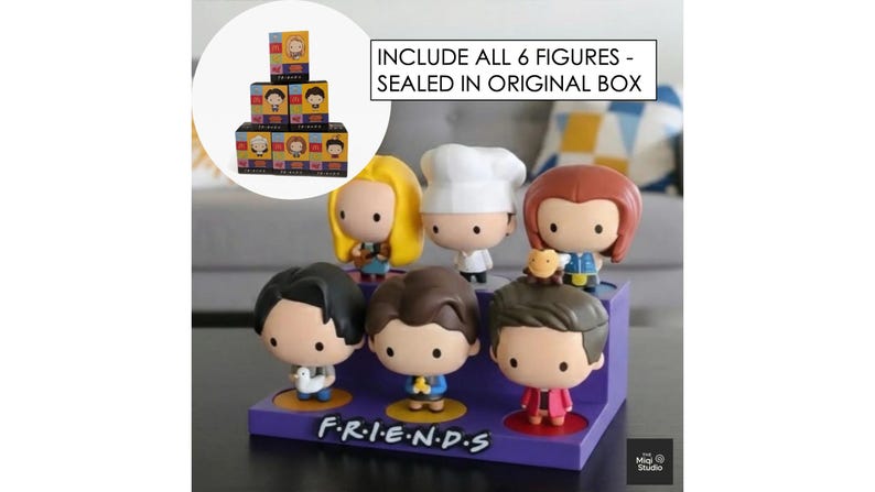 May include: A set of six Friends character figurines displayed on a purple base with the show's logo. The figures are in a cartoon style, each with unique outfits and hairstyles. The text "INCLUDE ALL 6 FIGURES - SEALED IN ORIGINAL BOX" is visible.