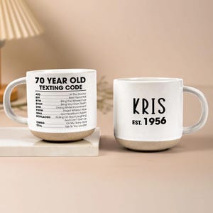 Op de afbeelding: Een set van drie keramische mokken met een gespikkelde, matte afwerking. De mokken zijn in tinten crème, lichtgrijs en donkergrijs. Elke mok heeft een eenvoudig, minimalistisch ontwerp, ideaal voor koffie of thee.