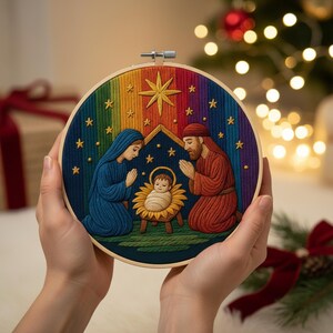 May include: A circular embroidery hoop with a Nativity scene. The image shows Mary, Joseph, and baby Jesus, set against a rainbow arch and stars. The figures are in blue and red, with a gold star at the top.