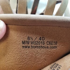 May include: Close-up of the inside of a tan leather sandal. The sandal's interior displays the size 8 1/2 / 40, along with the style code M/W W02016 CKE10 and the website www.bornshoes.com.