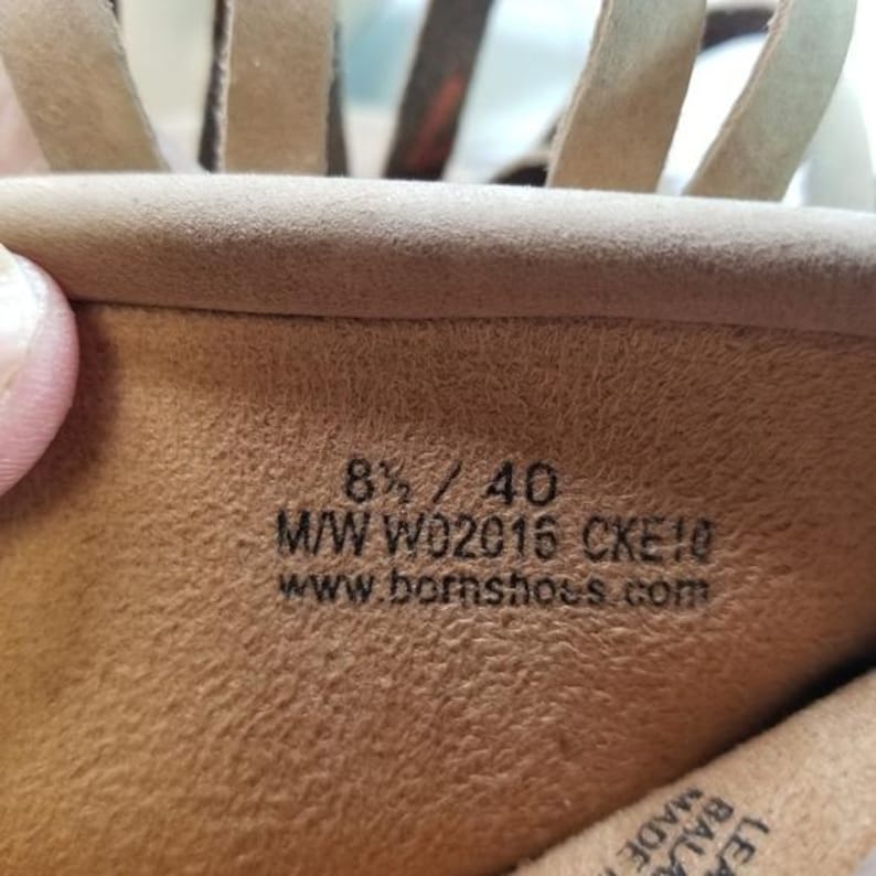 May include: Close-up of the inside of a tan leather sandal. The sandal's interior displays the size 8 1/2 / 40, along with the style code M/W W02016 CKE10 and the website www.bornshoes.com.