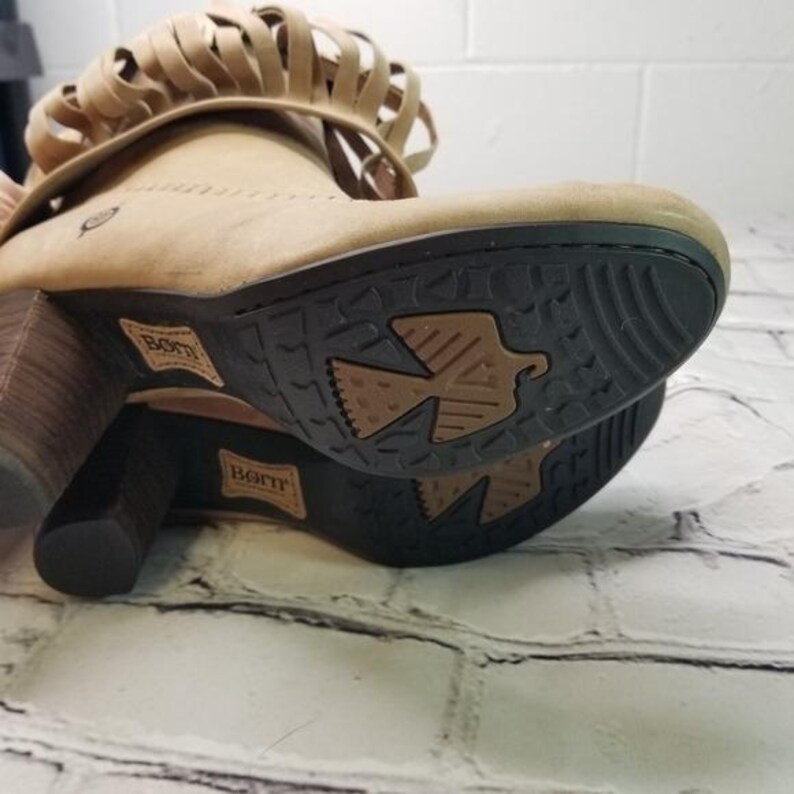 May include: Tan suede ankle boots with a stacked heel and fringe detail. The boots have a rubber sole with a bird design and the brand name "Born" is visible on the sole and side of the boot.
