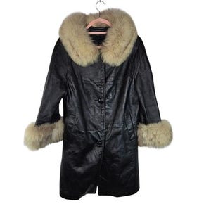 May include: Black leather coat with a light tan fur collar and cuffs. The coat is buttoned up and hanging on a pink hanger. The fur trim provides a luxurious contrast to the sleek black leather. A classic outerwear piece.