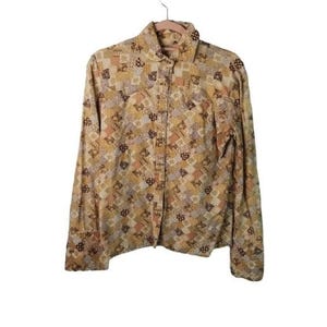 May include: A long-sleeved button-down shirt with a patchwork pattern in shades of brown, yellow, and cream.