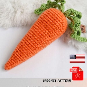 Puede incluir: Una zanahoria de ganchillo naranja con la parte superior verde y frondosa. La palabra "CARROT" se muestra en letras blancas grandes debajo de la zanahoria. Las palabras "CROCHET PATTERN" están encima de la palabra "CARROT". También se muestra un icono de descarga PDF y la bandera estadounidense.