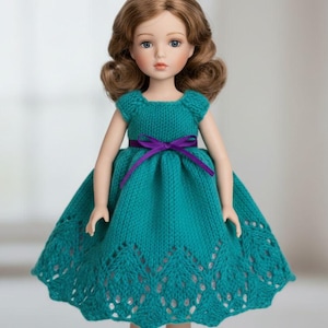Puede incluir: Muñeca con cabello castaño y ojos azules, vestida con un vestido de punto turquesa con una cinta morada. El vestido presenta un detallado calado en el dobladillo. Un juguete clásico.