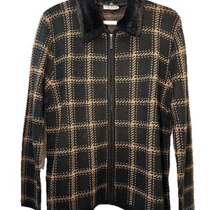 May include: A black and tan plaid zip-up jacket with a faux fur collar. The jacket features a full-length zipper and a classic plaid pattern. The jacket is a medium weight and appears to be made of a knit material.