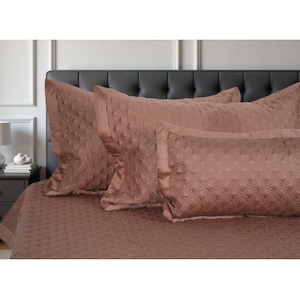 May include: A brown bed set with a quilted pattern, including a comforter and pillowcases. The bedding is displayed on a bed with a dark grey headboard. The color is a muted, earthy tone, suitable for a bedroom setting.