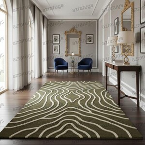May include: A rectangular olive green rug with a white, wavy pattern. The rug is placed on a dark wood floor in a room with large windows and a decorative wall mirror. The rug's design adds a modern touch to the room's decor.