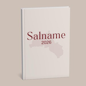 以下が含まれることがあります： 表紙に「Salname」の文字と「2026」の年号、地図の輪郭が描かれた、クリーム色のハードカバーノート。 ノートは白い背表紙です。