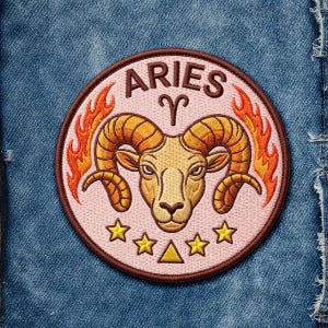 May include: Embroidered Aries zodiac patch. The round patch features a ram's head with large, curved horns, surrounded by flames. The word "ARIES" is arched above the ram. The patch is pink with gold, orange, and brown accents, and includes stars and a triangle.