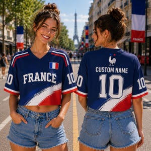 A woman wearing a blue and red France jersey with the number 10, standing on a street with the Eiffel Tower in the background.