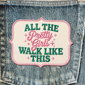 May include: Embroidered patch with the text "ALL THE Pretty Girls WALK LIKE THIS" in green and pink. The patch has a white background and a pink border, set against a denim pocket.