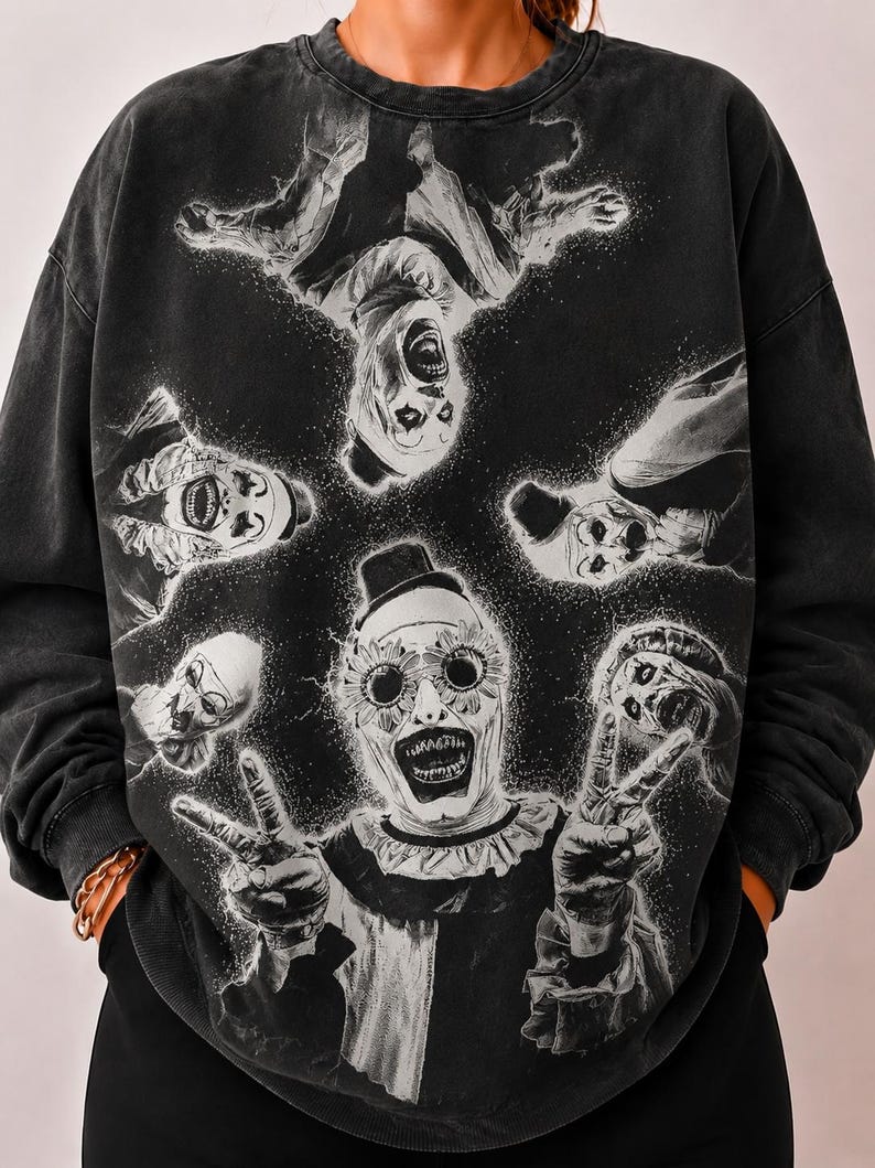 May include: A charcoal grey crewneck sweatshirt featuring a graphic print of five clowns in white face paint. The central clown wears sunflower-shaped glasses and makes a peace sign with both hands, while four other clowns surround it in a circular pattern.