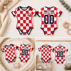 May include: A short-sleeved baby bodysuit featuring a red and white checkered pattern, navy blue trim, and the Croatian flag emblem. The back displays the text CUSTOM NAME above the number 00 in navy blue, with a small Croatian flag above the text.