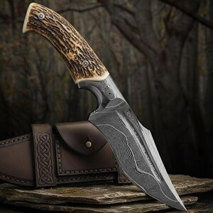 May include: A hunting knife with a patterned steel blade and a handle made of textured brown material. The knife is displayed with a brown leather sheath, showcasing a detailed design. The blade has a sharp point and a curved edge.