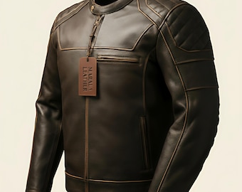 May include: A brown leather jacket with a quilted shoulder design and a stand-up collar. The jacket has a zipper closure and a small pocket on the chest. A tag that says "MARALA LEATHER" hangs from the zipper.