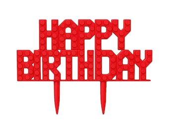 May include: A red "Happy Birthday" cake topper, designed to resemble toy building blocks. The text is in capital letters, with two pointed stakes at the bottom for insertion into a cake. The topper is made of a solid, vibrant red material.