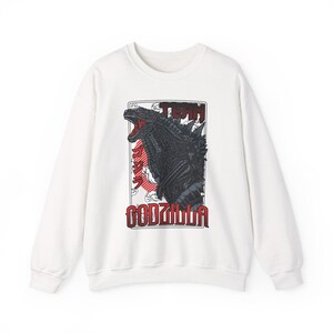 May include: White crew neck sweatshirt with a black Godzilla graphic and red accents, including Japanese text. The word "GODZILLA" is printed in red block letters below the graphic.