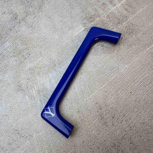 May include: A glossy, L-shaped royal blue handle featuring a smooth, reflective surface. The handle has a distinct angular design with a small, white geometric logo printed on the lower corner, showcasing a clean and modern aesthetic.