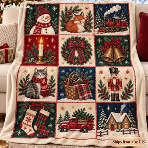 May include: A cream-colored fleece throw blanket featuring a grid of twelve festive Christmas illustrations, including a snowman, a fox, a steam train, a candle, a wreath, bells, a cat, a basket, a nutcracker, stockings, a truck, and a house.