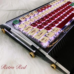 Puede incluir: Un teclado mecánico con un tema rojo retro. El teclado presenta teclas rojas y blanquecinas con retroiluminación. El marco es transparente con detalles negros y dorados. El texto "Retro Red" está en la parte inferior.