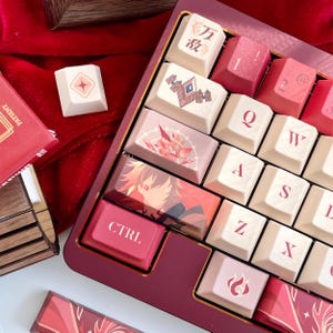May include: A custom mechanical keyboard with a burgundy frame and cream-colored keycaps. Some keycaps feature illustrations and text, including a "CTRL" key. The keyboard rests on a red velvet surface, with additional keycaps visible.