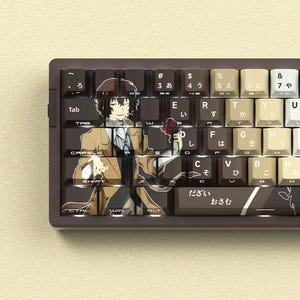 May include: A custom mechanical keyboard with keycaps featuring an anime character illustration. The keycaps are brown, beige, and white with Japanese characters and English letters. The keyboard has a dark brown frame.