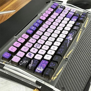 May include: Custom mechanical keyboard with purple and white keycaps. The keycaps feature various symbols and Japanese characters. The keyboard has a clear acrylic case and a dark gray base. The F keys are pink.