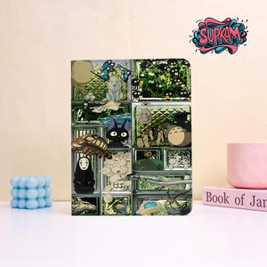 May include: A rectangular notebook cover featuring a grid of glass blocks, each containing various animated characters and creatures. The design includes a black cat, a white wolf, a large grey creature, and a black ghost-like figure.