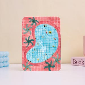 May include: A rectangular art print featuring a swimming pool scene. The pool is filled with swimmers and surrounded by palm trees. The border is a red tile pattern, and the pool water is blue. The print evokes a summer vacation theme.
