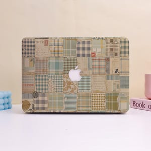 May include: Laptop case with a patchwork design featuring various patterns and colors, including plaid, floral, and text fragments. The case has a white Apple logo in the center.