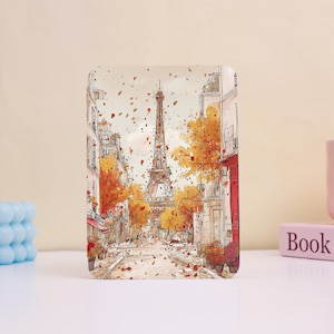 May include: A rectangular print featuring a watercolor illustration of the Eiffel Tower in Paris during autumn. The artwork depicts a street scene with buildings, trees with orange leaves, and falling foliage. The print has a soft, artistic aesthetic.