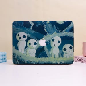 May include: A laptop case featuring a forest scene with four white, ghost-like figures with black eyes. The case has a dark blue background with green foliage and a white Apple logo.