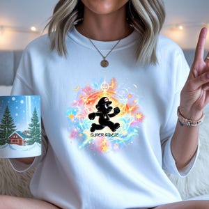 A smiling young girl next to a birthday cake wearing a white t-shirt featuring a custom Mario design with the text "Super ADELE".