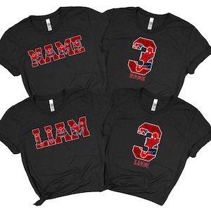 May include: Four black t-shirts with red and blue Spider-Man designs. Two shirts have the word "NAME" in red block letters with Spider-Man inside. The other two shirts have the number "3" with Spider-Man inside. One shirt says "LIAM" in red block letters.