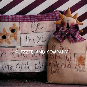 May include: A patriotic pillow with a red, white, and blue design and the text "Be true to the red white and blue". A small doll with a red, white, and blue bow and a pocket with a star is holding a small American flag.