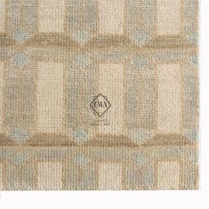 Peut inclure: Un tapis tufté présentant un motif géométrique en grille dans des tons crème, beige et vert sauge doux. Le design se compose de bandes verticales et horizontales entrecoupées de petits losanges. Un logo avec le texte CWA CARPET WORLD ART est visible.