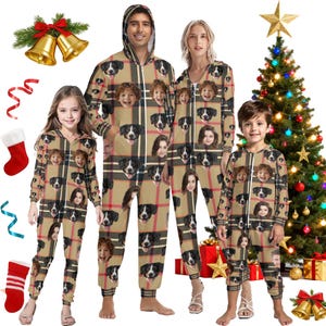 Op de afbeelding: Familie bijpassende geruite pyjama's met aangepaste gezichten van honden en mensen. De pyjama's zijn bruin met een zwart en rood geruit patroon. De familie staat voor een kerstboom.
