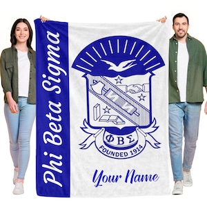 May include: A white and blue Phi Beta Sigma blanket. The blanket features the Greek letters ΦΒΣ, the words "Founded 1914", and a crest design. The words "Phi Beta Sigma" are written vertically in blue. The words "Your Name" are written in blue.
