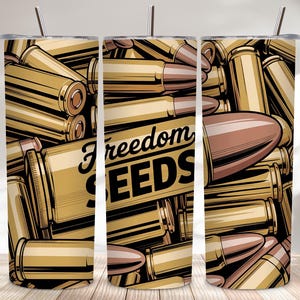Puede incluir: Tres vasos de acero inoxidable con un diseño de balas doradas y las palabras "Freedom Seeds" en escritura negra. Los vasos tienen una pajita plateada y un fondo negro.