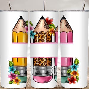 May include: White tumbler featuring three pencil designs with floral accents. The pencils are yellow, leopard print, and pink, each with a black tip. The design includes a space for personalization.