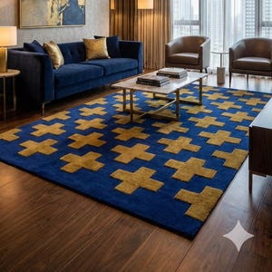 Könnte beinhalten: Modernes Wohnzimmer mit marineblauem Sofa, goldenen Kissen und zwei braunen Ledersesseln. Ein blau-gold gemusterter Teppich bedeckt den Boden. Ein abstraktes Gemälde und ein goldener Kronleuchter ergänzen die Einrichtung.
