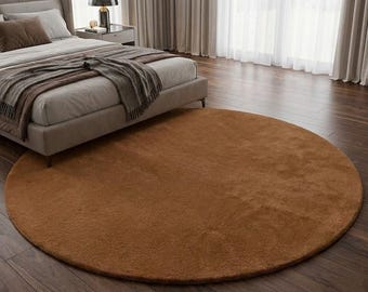 Puede incluir: Una alfombra redonda marrón con una textura suave y afelpada. La alfombra está colocada sobre un suelo de madera oscura en un dormitorio, cerca de una cama y cortinas. El diámetro de la alfombra es de aproximadamente 244 cm.