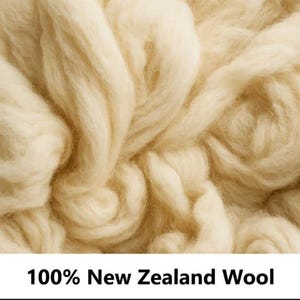 May include: A close-up view of soft, off-white New Zealand wool fibers with a fluffy, textured appearance. The image includes the text 100% New Zealand Wool printed in black at the bottom, indicating the material composition of the raw wool.