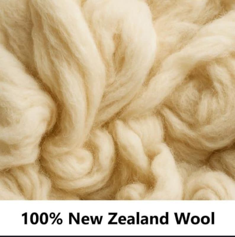 May include: A close-up view of soft, off-white New Zealand wool fibers with a fluffy, textured appearance. The image includes the text 100% New Zealand Wool printed in black at the bottom, indicating the material composition of the raw wool.