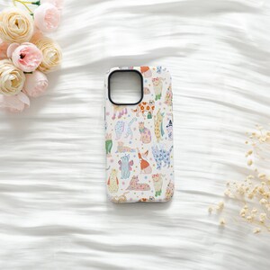 May include: A white smartphone case featuring a repeating pattern of various cats in different colors, poses, and outfits, including cats with floral prints, sweaters, and accessories, interspersed with small colorful stars and dots.