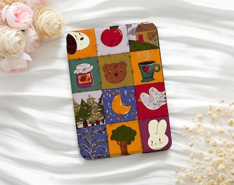 May include: A colorful, patchwork-style phone case featuring various whimsical illustrations. The design includes a red apple, a bear, a house, a jar of jam, a cup of coffee, a moon, a tree, a bird, and a bunny.