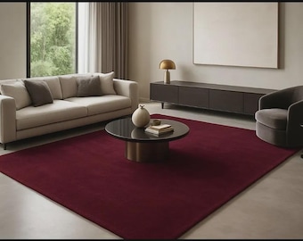 Puede incluir: Un salón moderno con una alfombra burdeos, un sofá beige con cojines y una mesa de centro marrón oscuro. También hay un mueble oscuro y un sillón gris. Una lámpara dorada y un jarrón están sobre la mesa de centro.