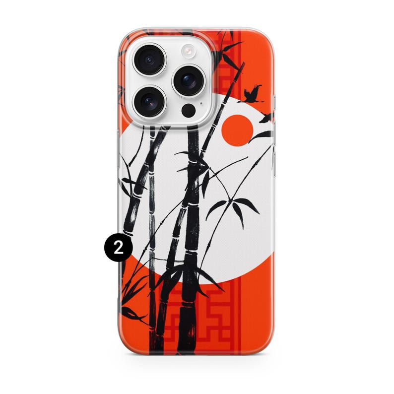 May include: A phone case featuring a Japanese-inspired design. The case has a clear border and a vibrant orange background. Black bamboo stalks and leaves are set against a white circle, with a red sun and flying birds. The number "2" is visible.